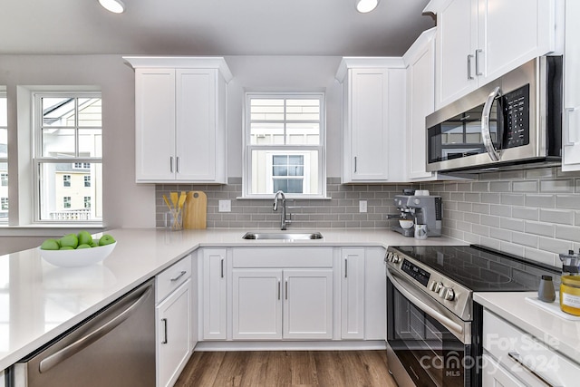 kitchen featuring plenty of natural light, stainless steel appliances, sink, white cabinets, and hardwood / wood-style flooring