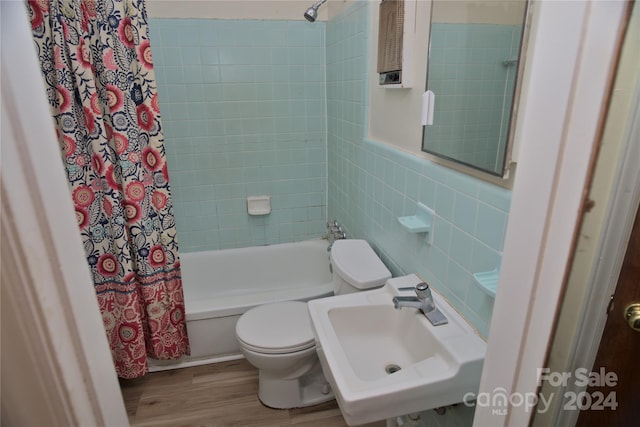 full bathroom featuring shower / tub combo with curtain, sink, wood-type flooring, tile walls, and toilet