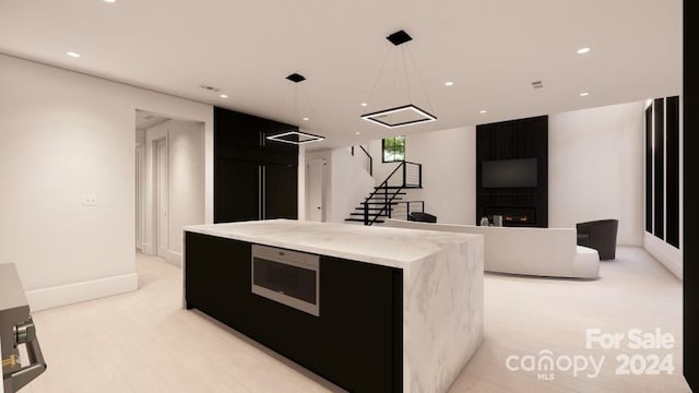 kitchen with decorative light fixtures, a fireplace, built in appliances, and a kitchen island