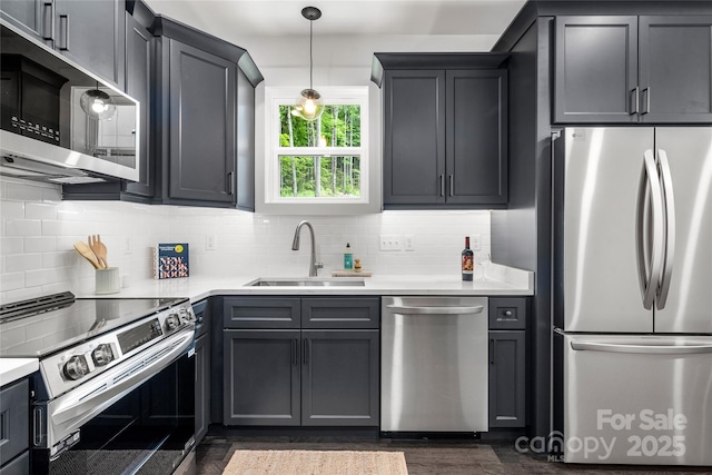 kitchen featuring tasteful backsplash, stainless steel appliances, dark wood-type flooring, sink, and decorative light fixtures