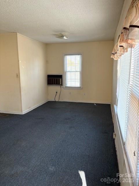 carpeted spare room featuring an AC wall unit and a textured ceiling