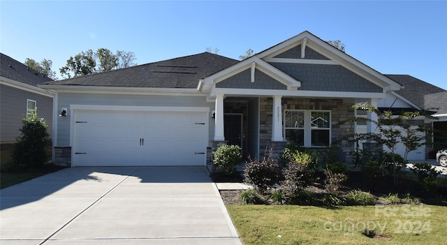 craftsman inspired home featuring a garage and a front lawn