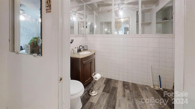 bathroom featuring built in features, hardwood / wood-style floors, toilet, vanity, and tile walls