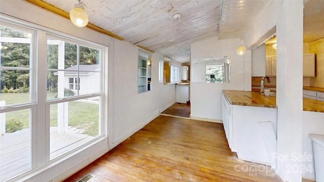 hall with light hardwood / wood-style flooring, wood ceiling, and sink