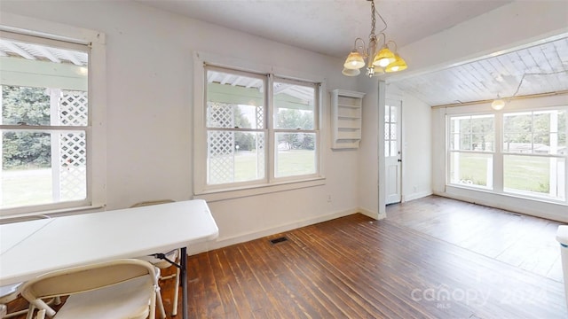 dining room featuring plenty of natural light, dark wood-type flooring, a chandelier, and vaulted ceiling