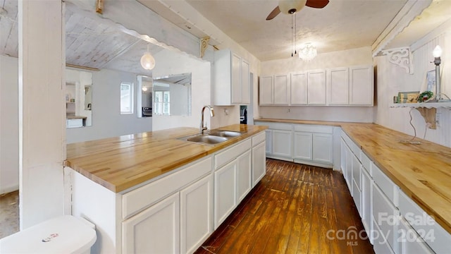 kitchen with wood counters, sink, white cabinetry, and hanging light fixtures