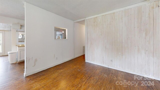 unfurnished room featuring dark hardwood / wood-style flooring and wooden walls