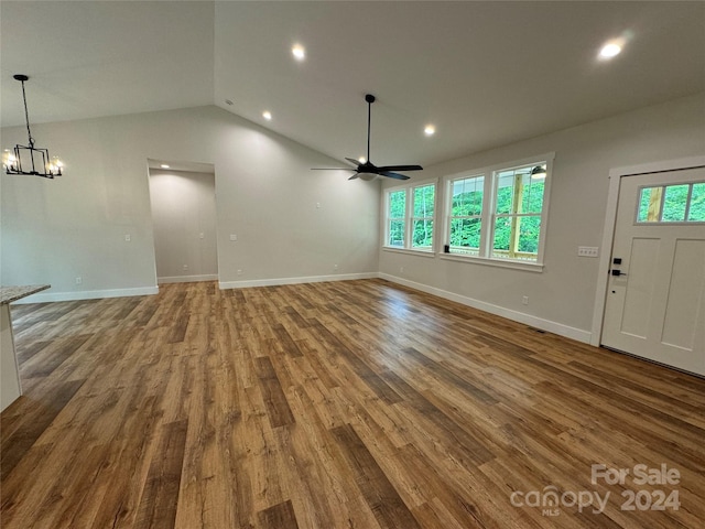 unfurnished living room featuring ceiling fan with notable chandelier, lofted ceiling, and hardwood / wood-style flooring