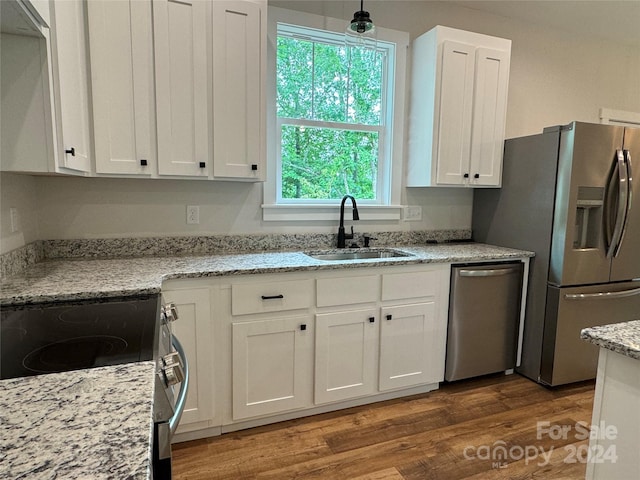 kitchen with light stone counters, stainless steel appliances, sink, pendant lighting, and white cabinetry