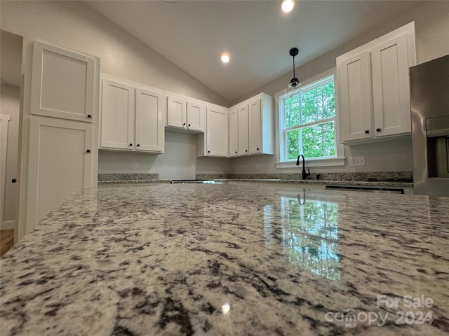 kitchen with light stone countertops, white cabinets, pendant lighting, and vaulted ceiling