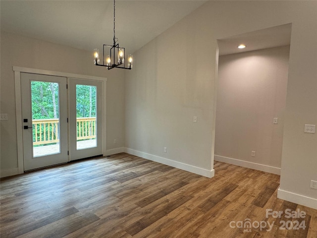 unfurnished dining area featuring lofted ceiling, wood-type flooring, and an inviting chandelier