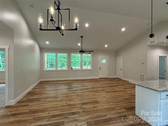 interior space featuring ceiling fan with notable chandelier, lofted ceiling, and dark wood-type flooring