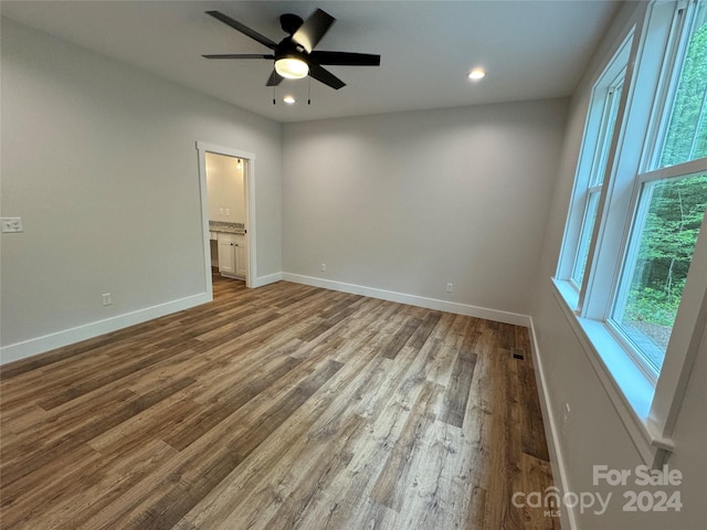 unfurnished bedroom with hardwood / wood-style floors, connected bathroom, and ceiling fan