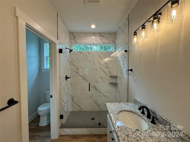 bathroom featuring hardwood / wood-style floors, vanity, a shower with shower door, and toilet