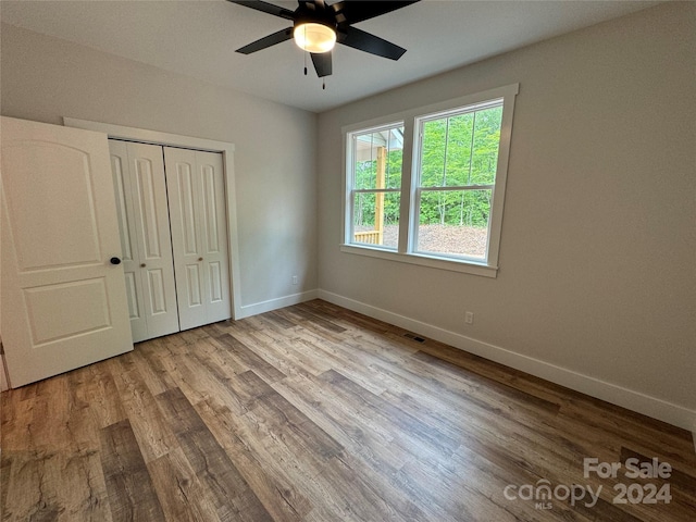 unfurnished bedroom with ceiling fan, a closet, and light wood-type flooring