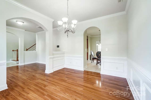 unfurnished dining area with crown molding, light wood-type flooring, and a chandelier