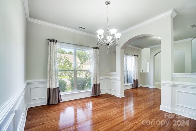 unfurnished dining area with hardwood / wood-style flooring, ornamental molding, and a notable chandelier