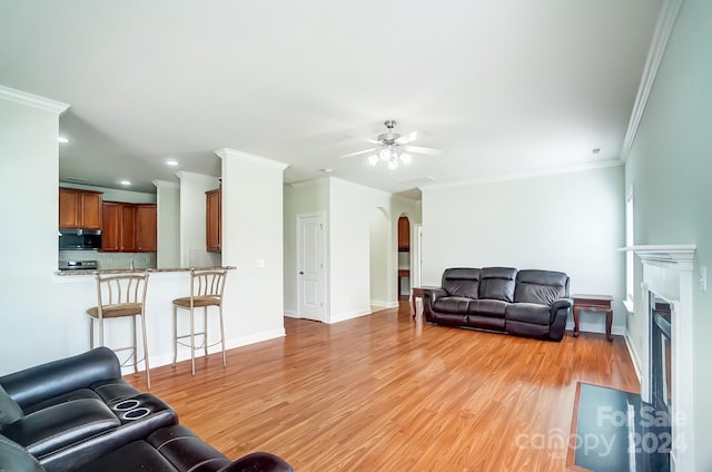 living room featuring ornamental molding, ceiling fan, and light wood-type flooring