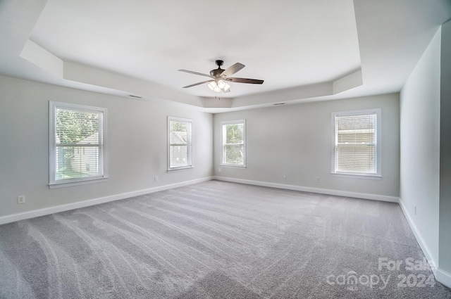 empty room featuring light carpet, ceiling fan, and a tray ceiling