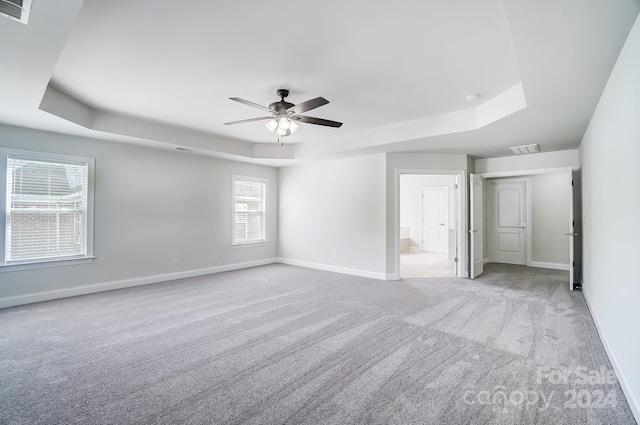 unfurnished room with light colored carpet, a raised ceiling, and ceiling fan