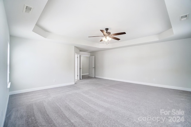 spare room with ceiling fan, a raised ceiling, and carpet floors