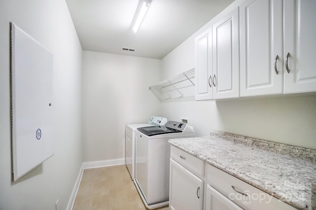 laundry room featuring light hardwood / wood-style floors, washing machine and dryer, and cabinets