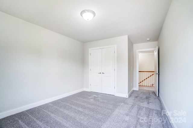 unfurnished bedroom featuring light carpet and a closet