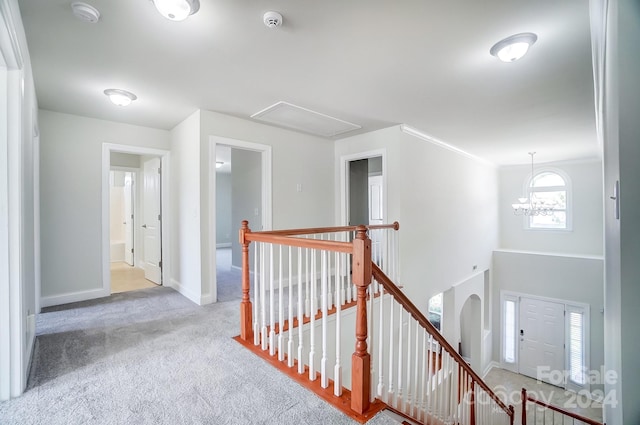 hallway featuring an inviting chandelier, light colored carpet, and ornamental molding