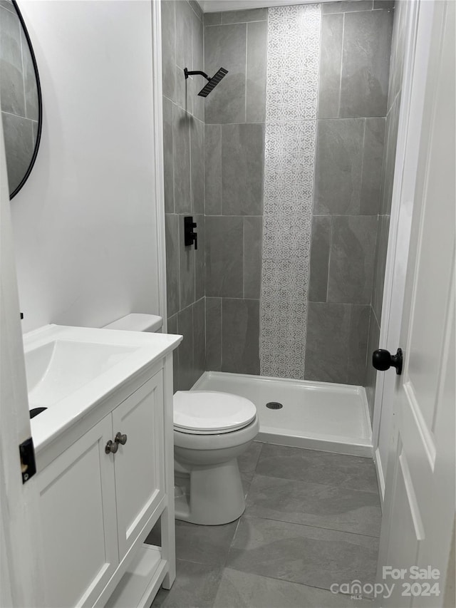 bathroom featuring tiled shower, vanity, and toilet