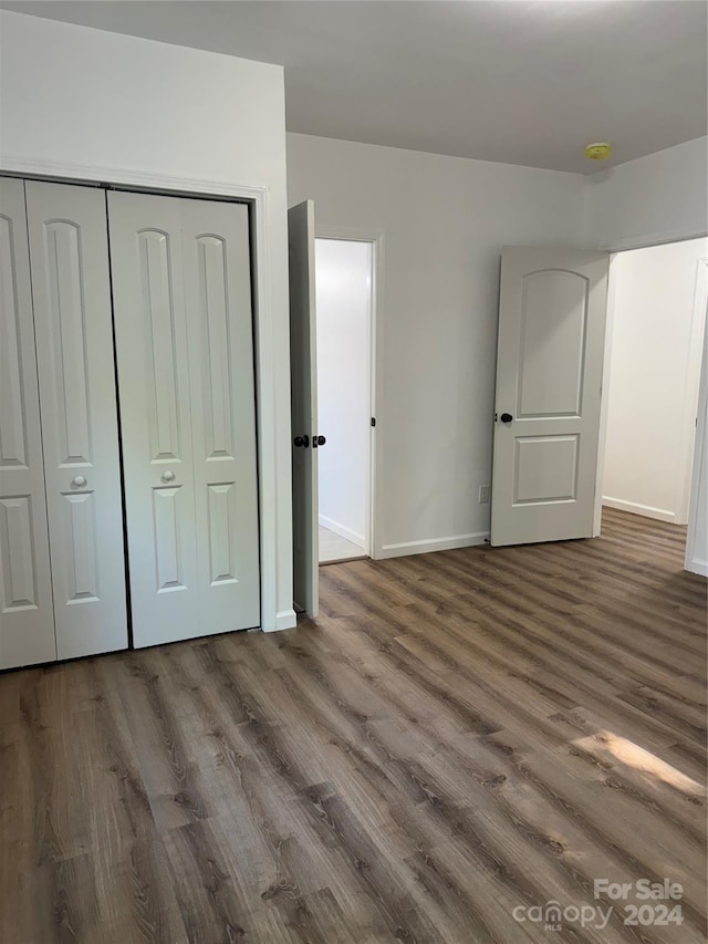 unfurnished bedroom with dark hardwood / wood-style flooring and a closet