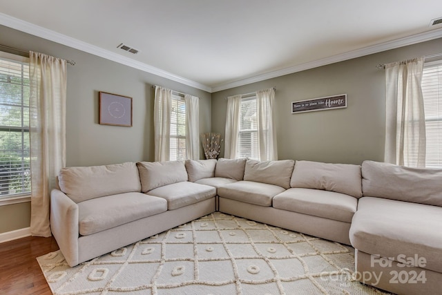 living room with crown molding, plenty of natural light, and light hardwood / wood-style floors