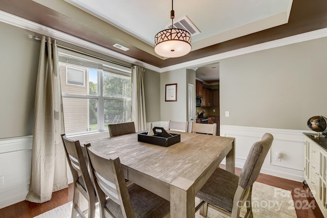 dining room featuring hardwood / wood-style flooring, a raised ceiling, and crown molding