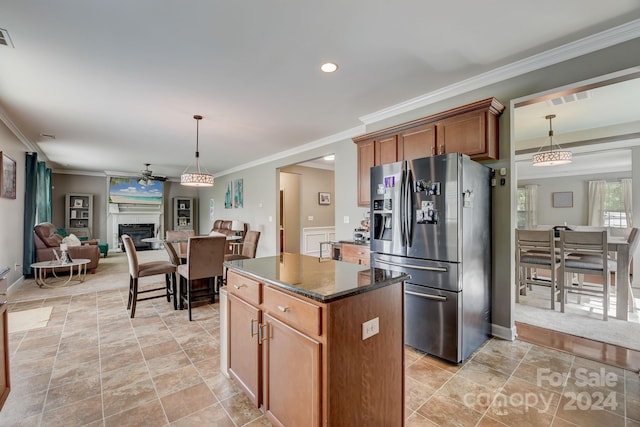 kitchen featuring a center island, dark stone counters, crown molding, stainless steel refrigerator with ice dispenser, and ceiling fan