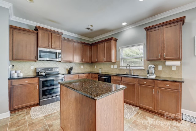 kitchen featuring appliances with stainless steel finishes, crown molding, sink, dark stone countertops, and a kitchen island