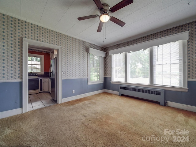 carpeted empty room with ceiling fan and radiator heating unit