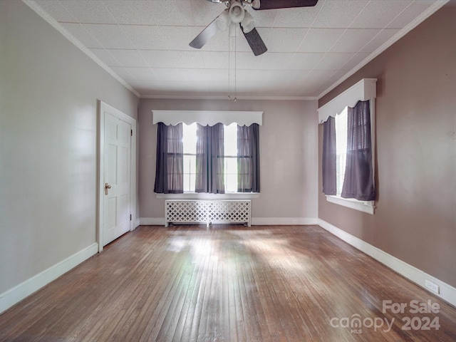 unfurnished room featuring ceiling fan, hardwood / wood-style floors, radiator heating unit, and ornamental molding