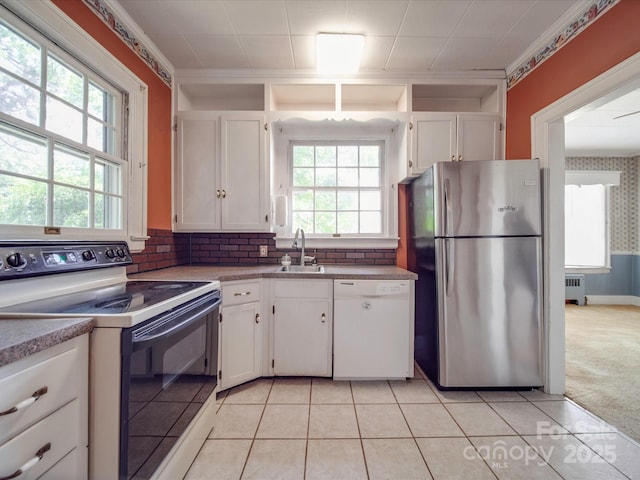 kitchen with radiator heating unit, a wealth of natural light, white cabinetry, sink, and white appliances