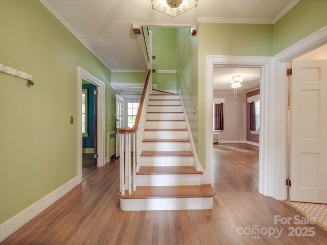 staircase with crown molding, plenty of natural light, and hardwood / wood-style floors