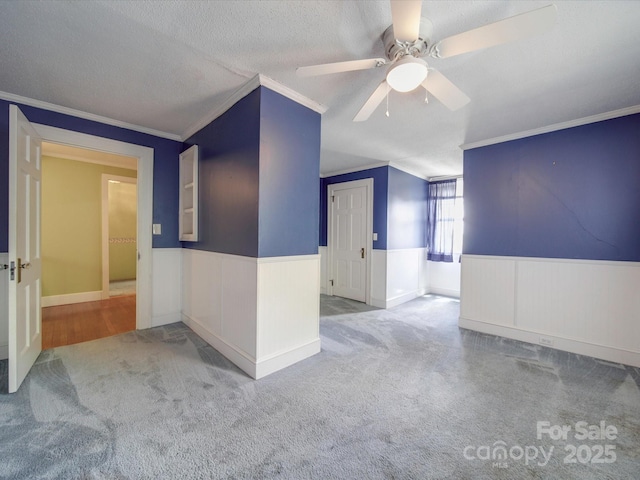 spare room featuring crown molding, ceiling fan, carpet flooring, and a textured ceiling