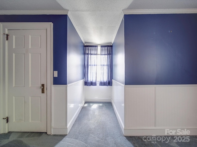 hall with ornamental molding, carpet, and a textured ceiling