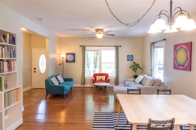 living room with hardwood / wood-style floors, ceiling fan with notable chandelier, built in features, and a wealth of natural light