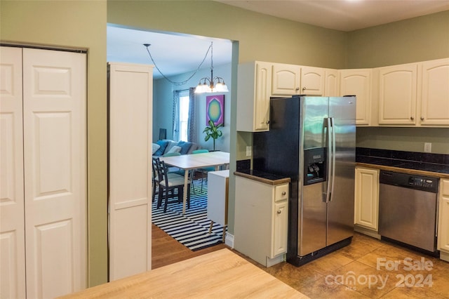 kitchen with appliances with stainless steel finishes, decorative light fixtures, a notable chandelier, white cabinets, and light tile patterned flooring