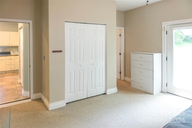 unfurnished bedroom with light colored carpet and a closet