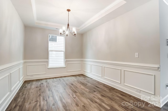 unfurnished room featuring hardwood / wood-style floors, a raised ceiling, crown molding, and a chandelier