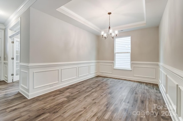 unfurnished room featuring a raised ceiling, crown molding, hardwood / wood-style floors, and an inviting chandelier