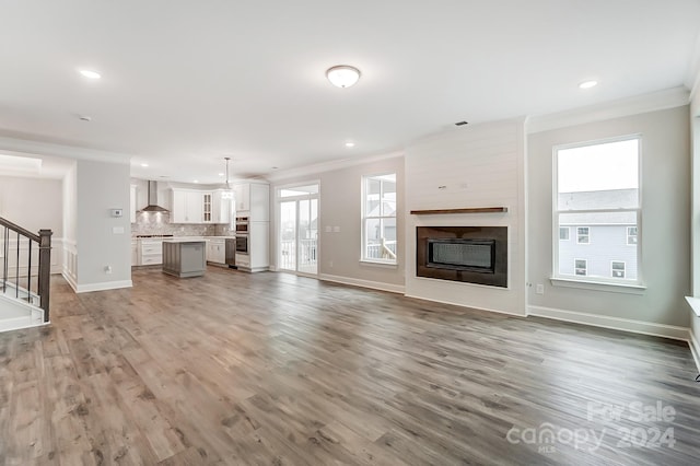 unfurnished living room featuring a fireplace, wood-type flooring, and ornamental molding