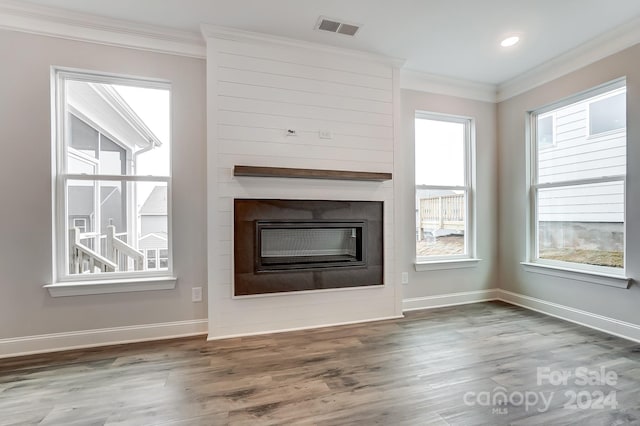 unfurnished living room featuring a fireplace, wood-type flooring, and crown molding