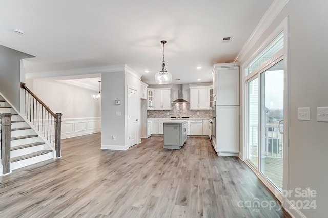 kitchen featuring a center island, pendant lighting, wall chimney range hood, and light hardwood / wood-style flooring