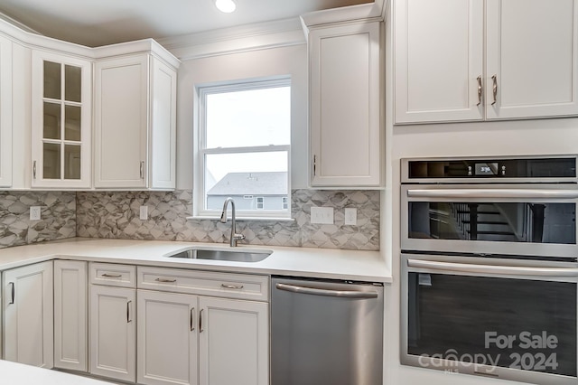 kitchen featuring white cabinets, appliances with stainless steel finishes, backsplash, and sink