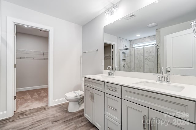 bathroom with vanity, wood-type flooring, a shower with shower door, and toilet